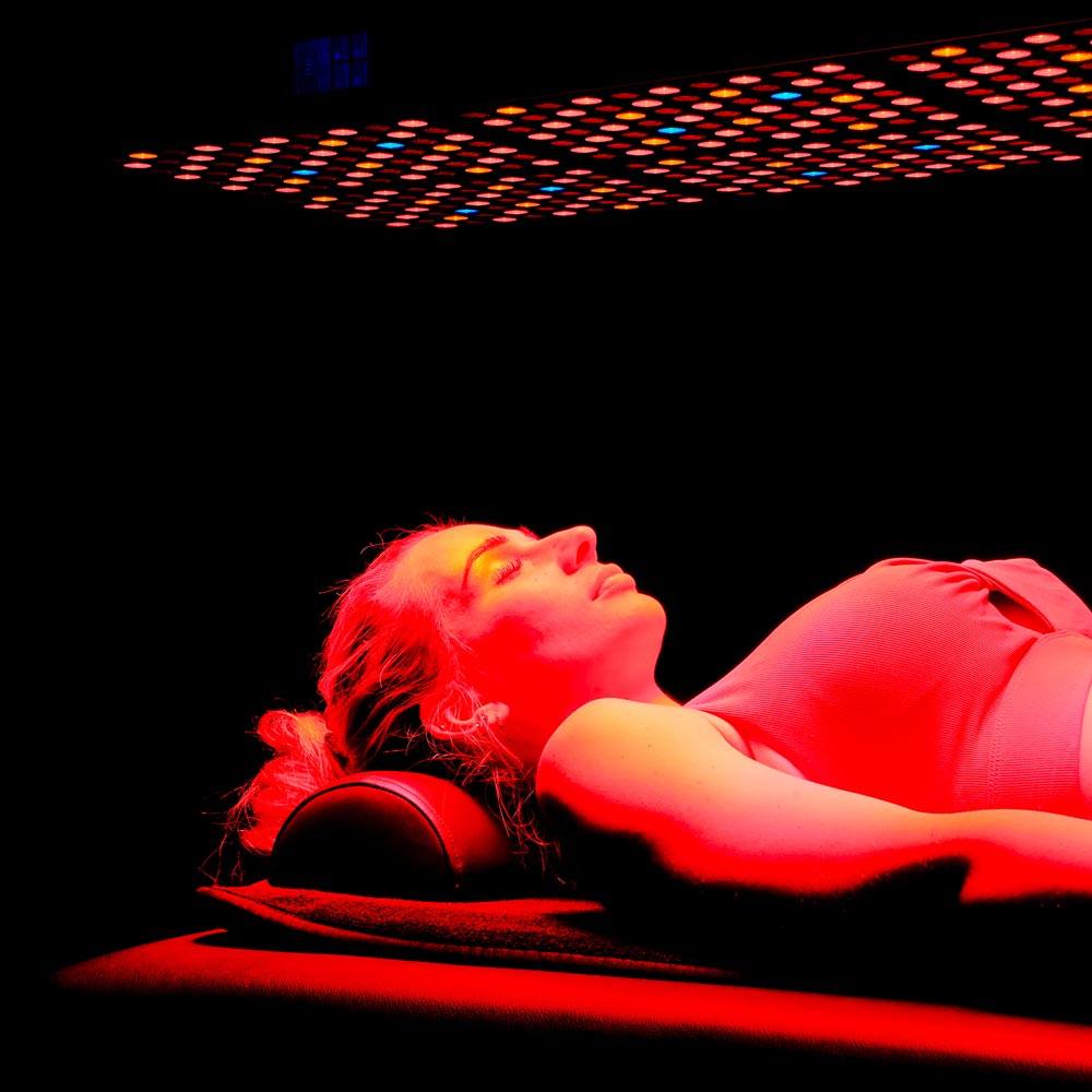 Lady laying under red light panel